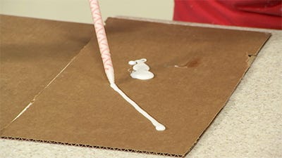 dispensing adhesive on piece of cardboard to ensure the mixture of adhesive is correct