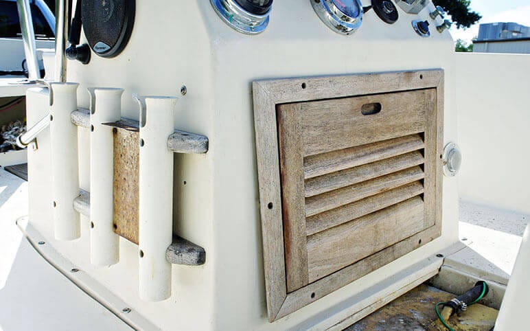 Worn teak console door and rod holders on center console boat